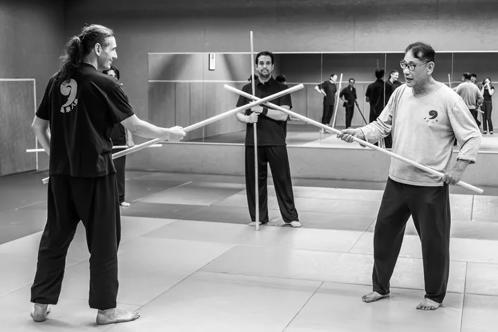 Travail de l'épée du Xingyi Quan : trois pratiquants croisent les armes.